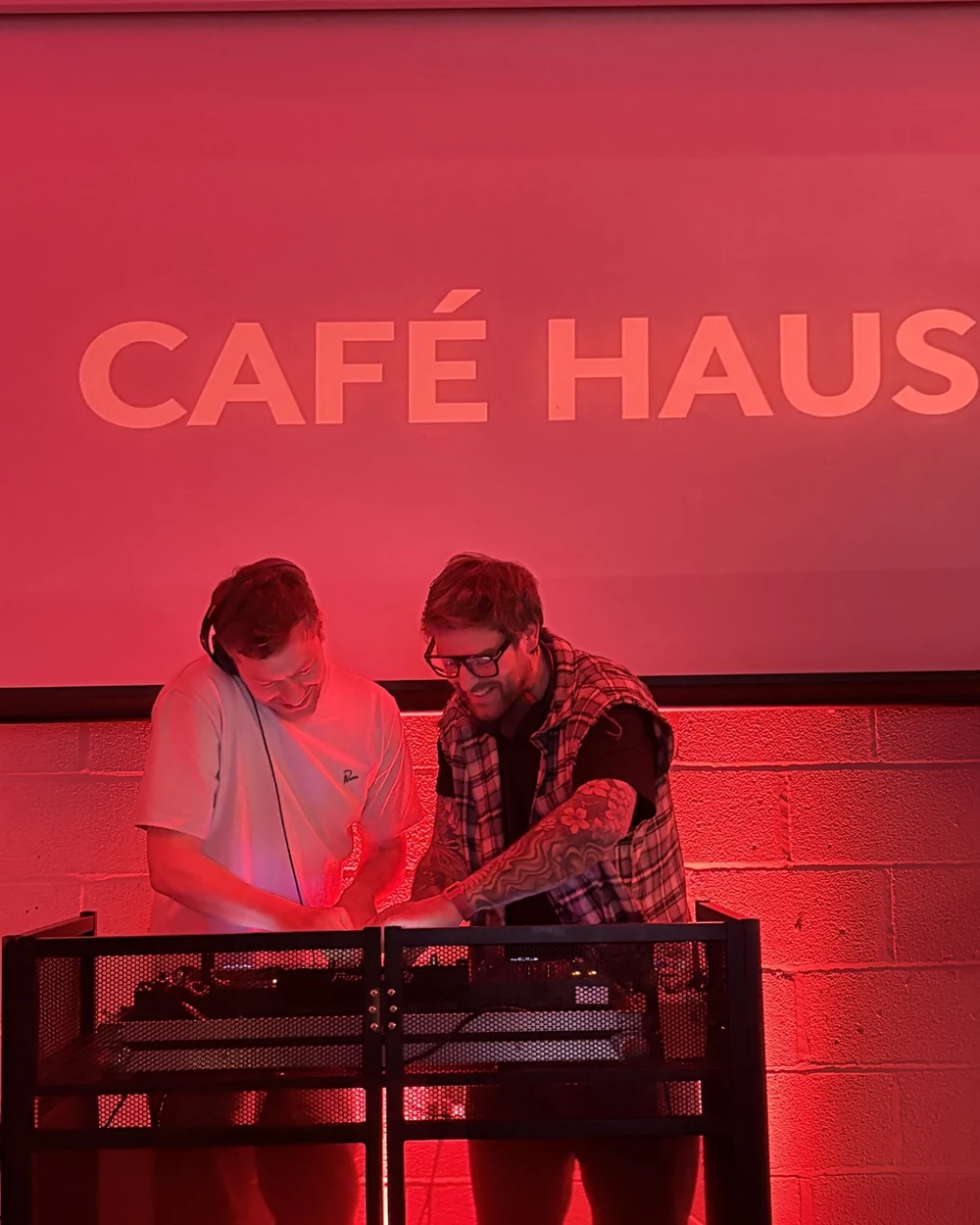 CAFE HAUS performing under the venue's pink CAFE HAUS lettering